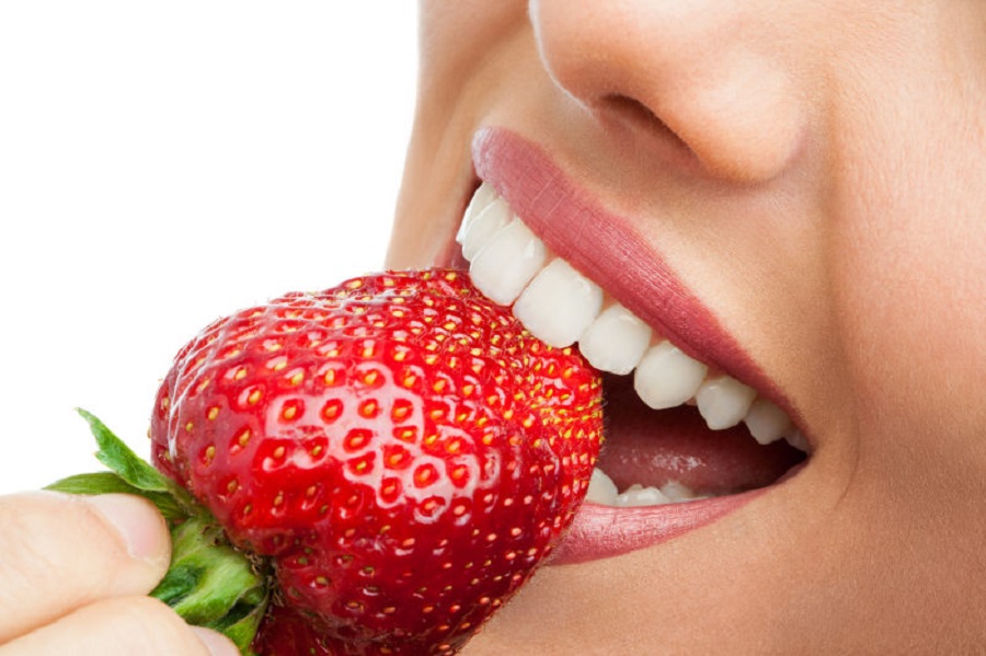 Macro close up of woman's mouth eating strawberry.